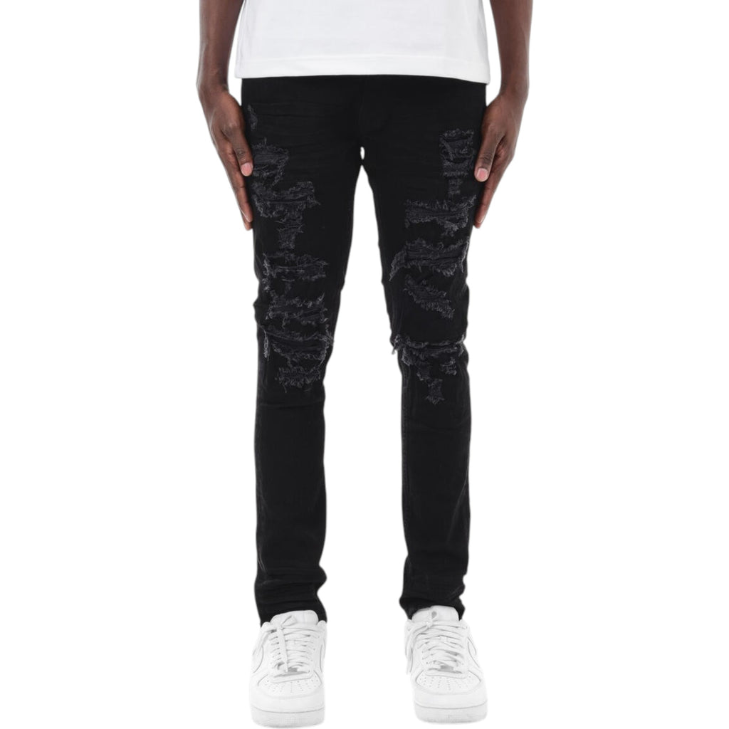 Person wearing black distressed jeans and white sneakers on a white background