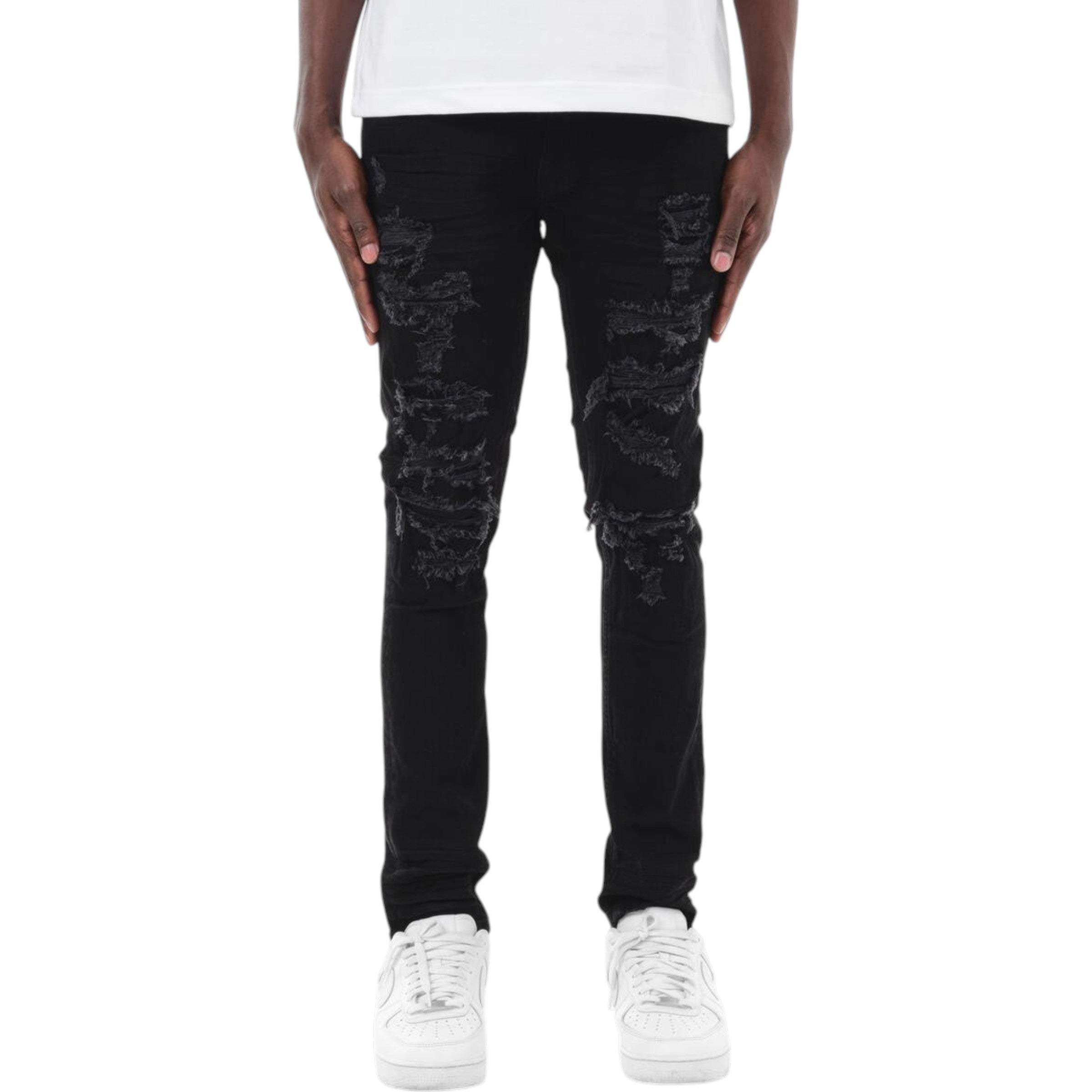 Person wearing black distressed jeans and white sneakers on a white background