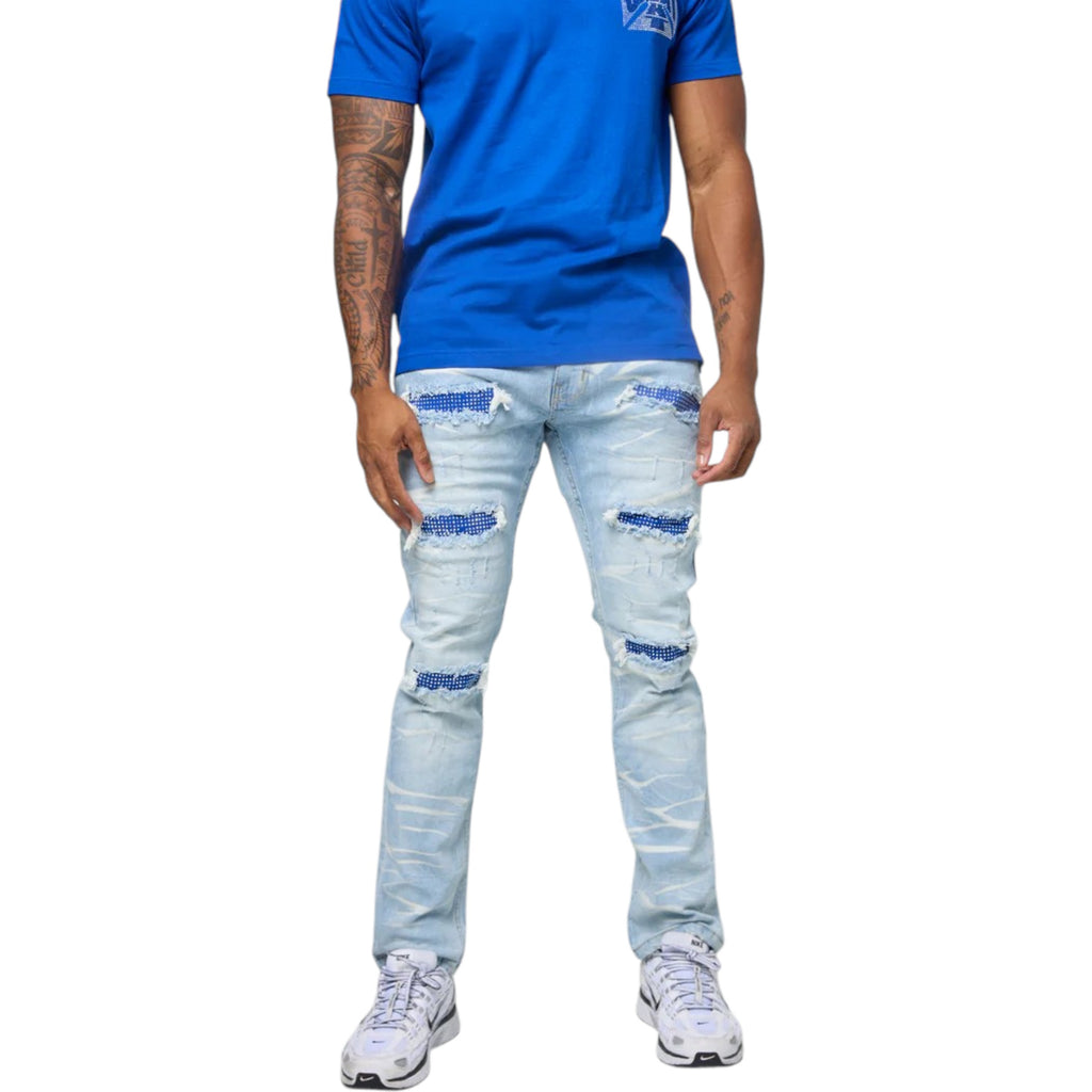 Person wearing a blue t-shirt and light blue ripped jeans on a white background