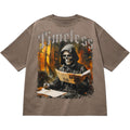 Brown t-shirt with a graphic of a skeleton reading a newspaper titled 'Timeless'.