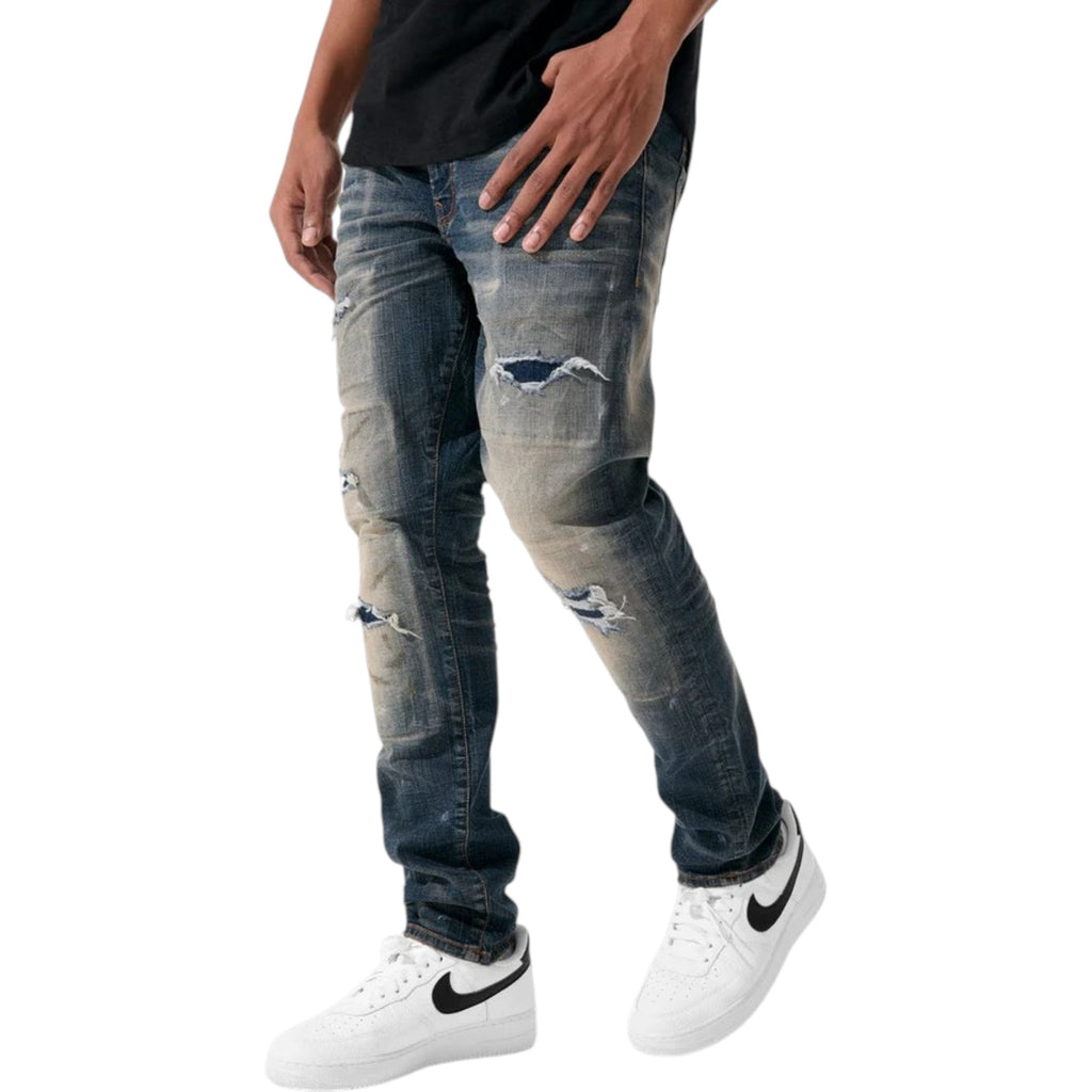 Person wearing distressed blue jeans and white sneakers on a white background