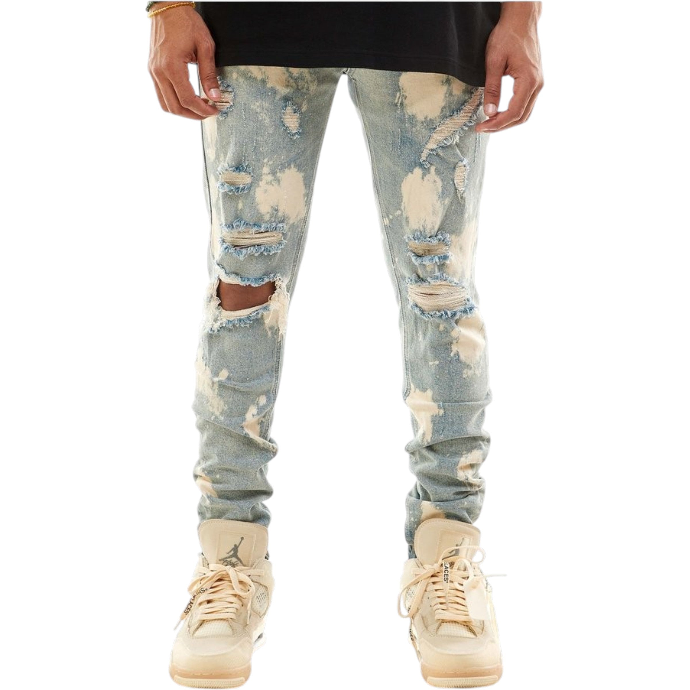 Ripped light blue jeans worn with beige sneakers on a white background