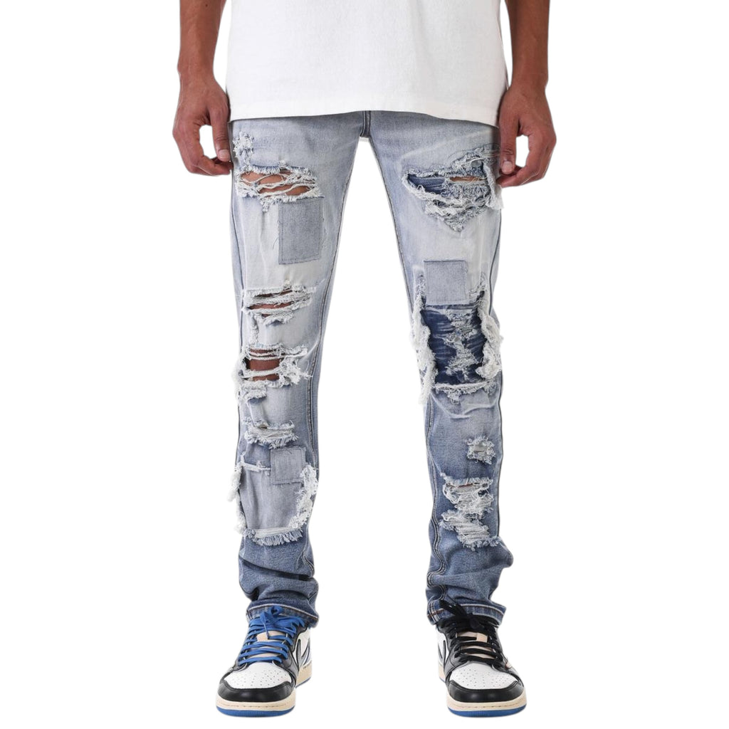 Distressed blue jeans worn by a person on a white background