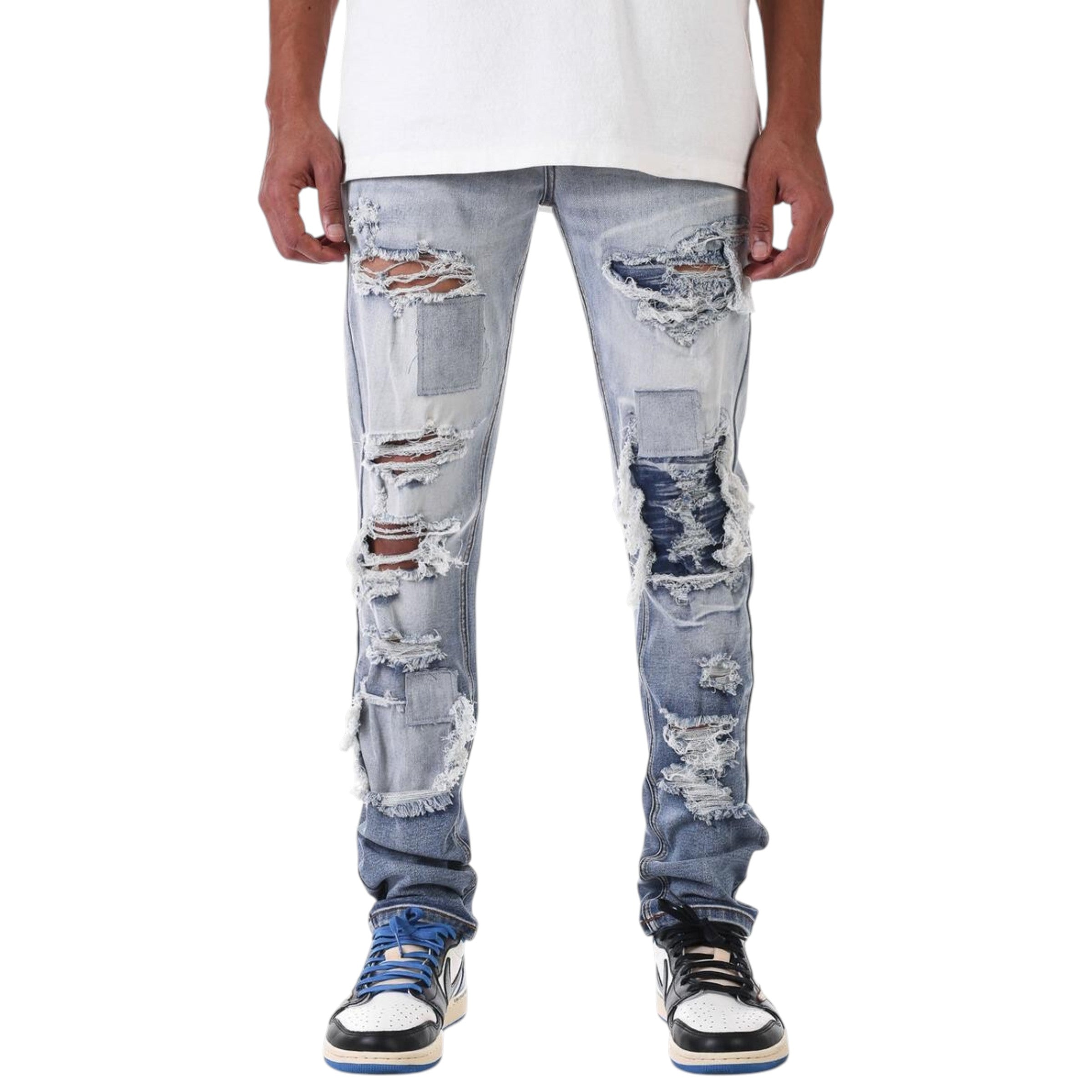 Distressed blue jeans worn by a person on a white background