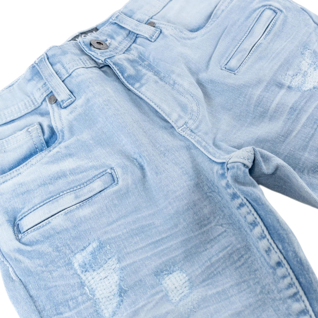 Close-up of light blue denim jeans with distressing details on a white background biker denim kids jeans 