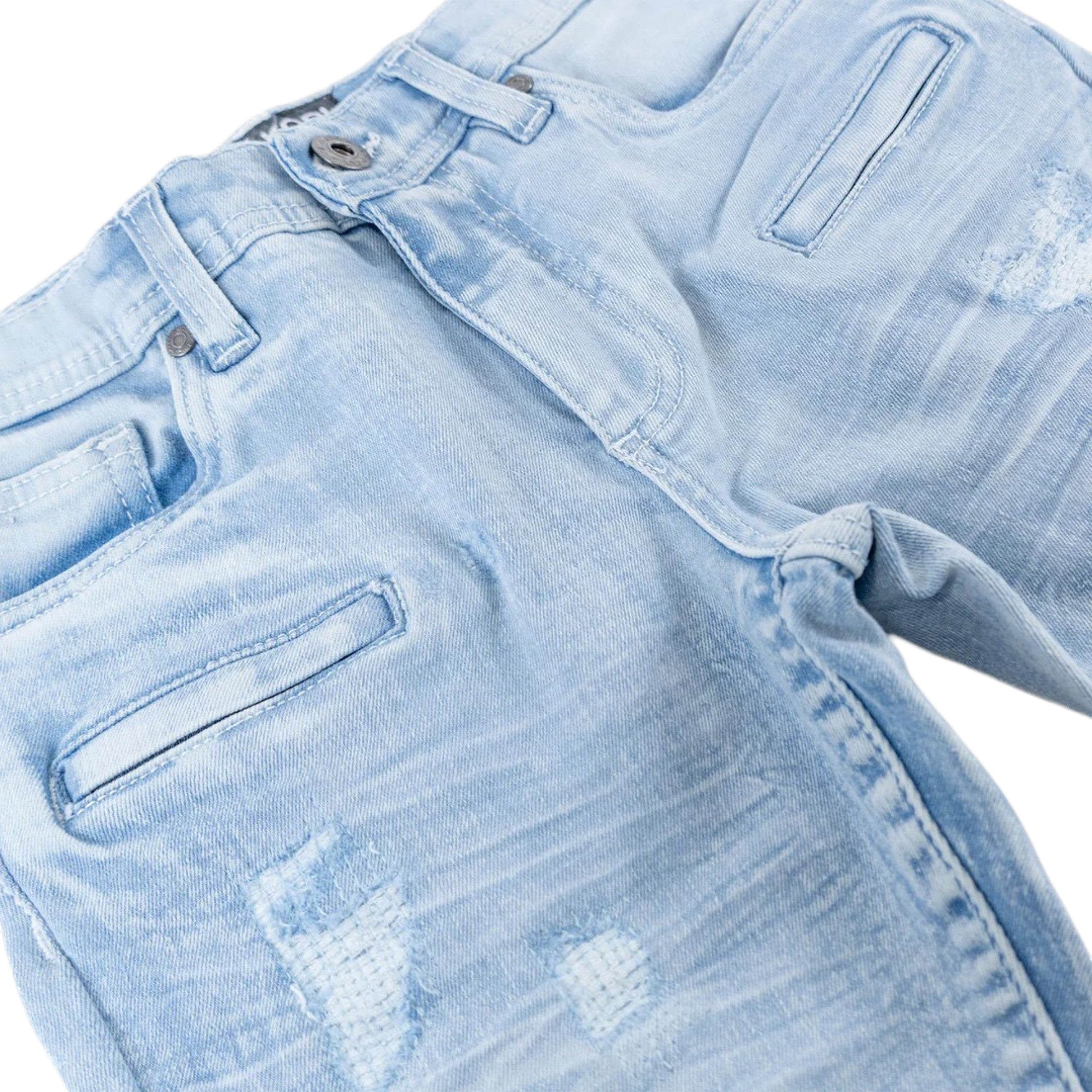 Close-up of light blue denim jeans with distressing details on a white background biker denim kids jeans 