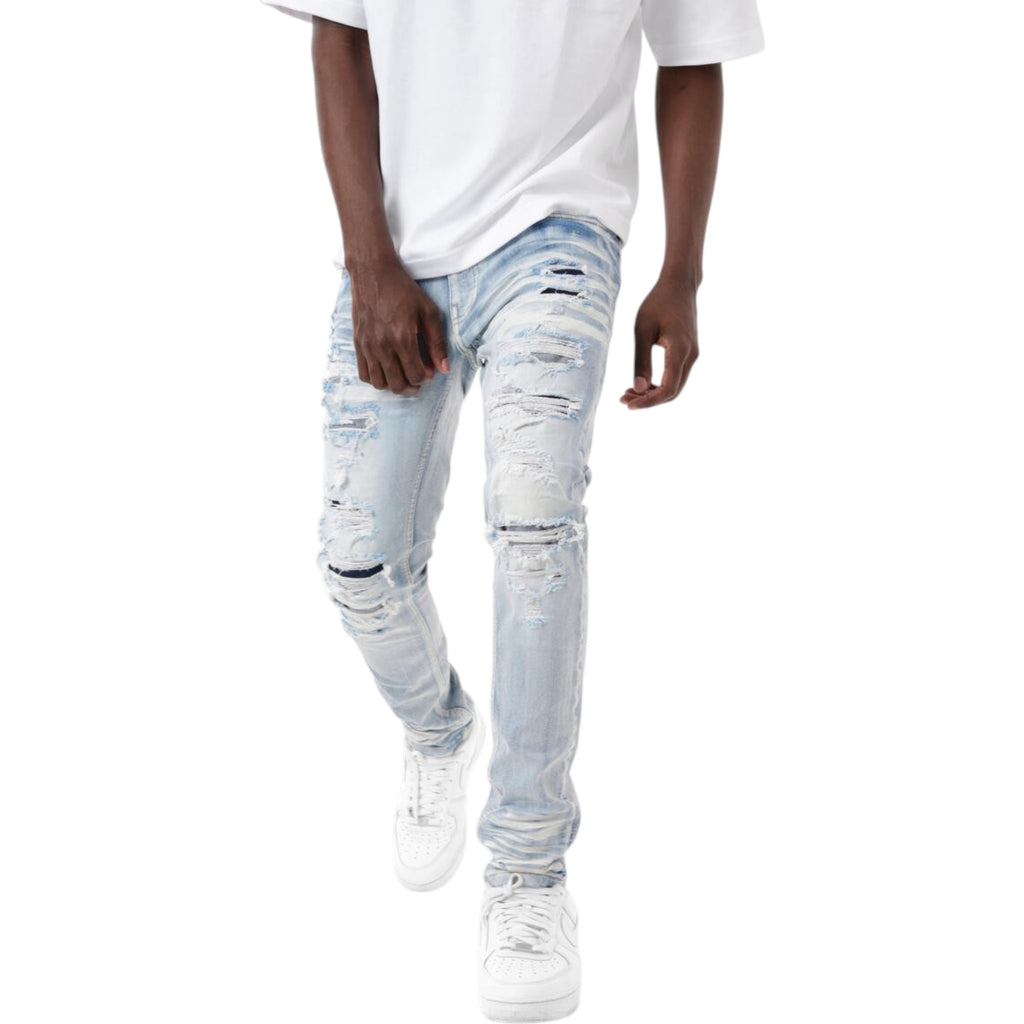 Person wearing light blue distressed jeans and white sneakers on a white background