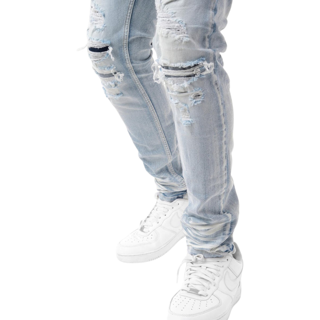 Light blue distressed jeans with white sneakers on a white background