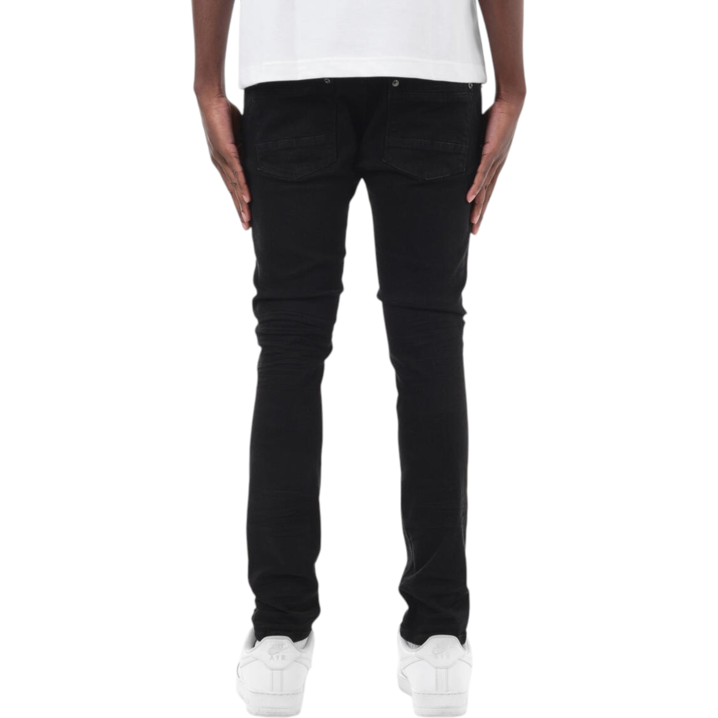 Person wearing black jeans and white sneakers on a white background