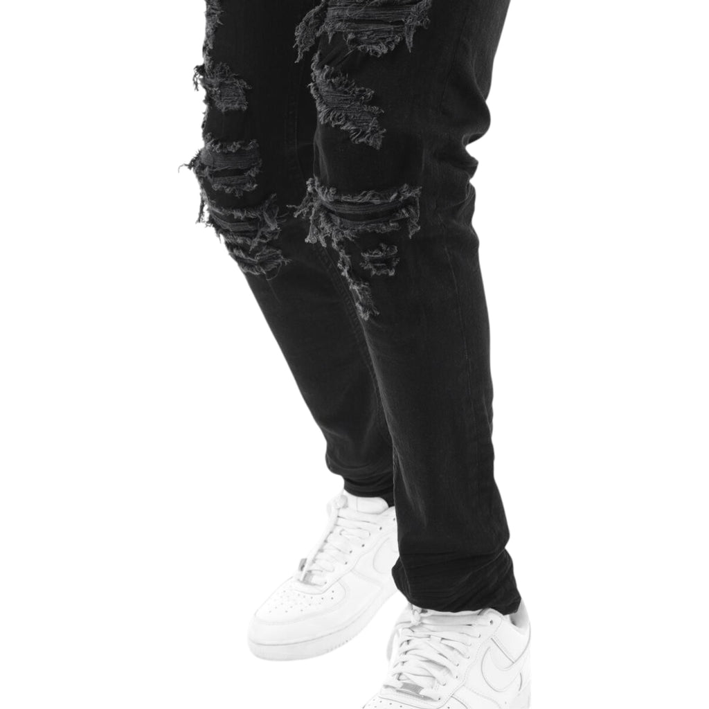 Black distressed jeans worn with white sneakers on a white background