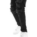 Black distressed jeans worn with white sneakers on a white background