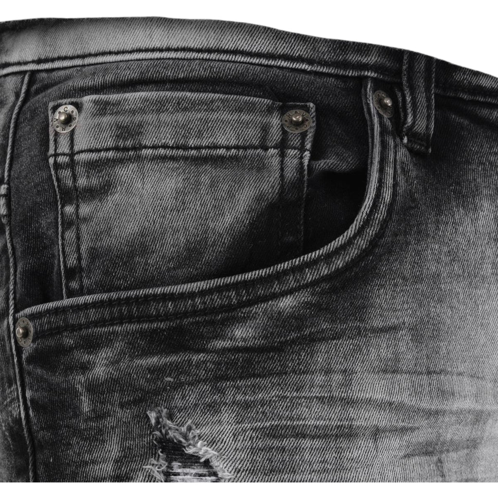 Close-up of a black distressed denim pocket with stitching details.