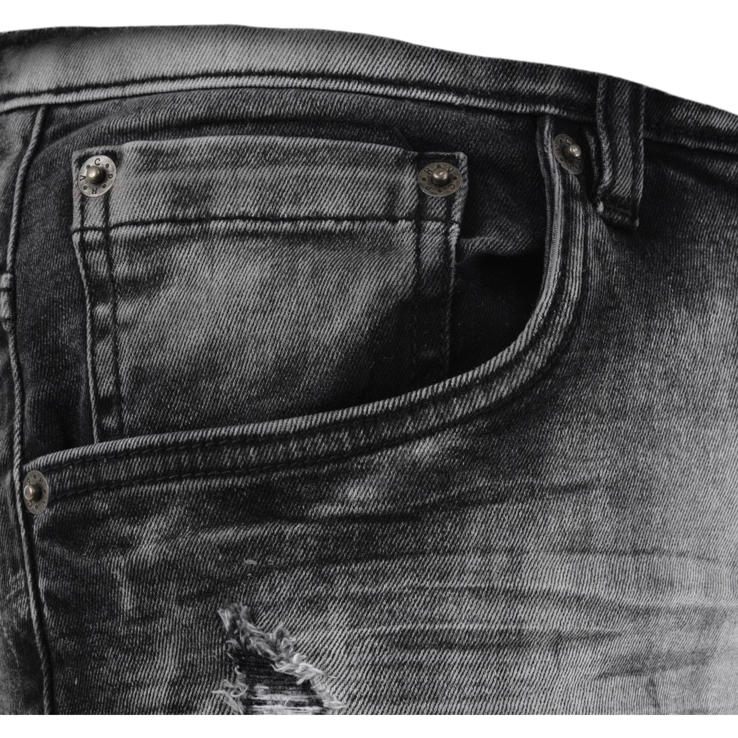 Close-up of a black distressed denim pocket with stitching details.