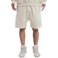 Person wearing a beige tracksuit with shorts and white sneakers on a white background