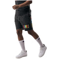 Person wearing black denim shorts with colorful text and white sneakers on a white background