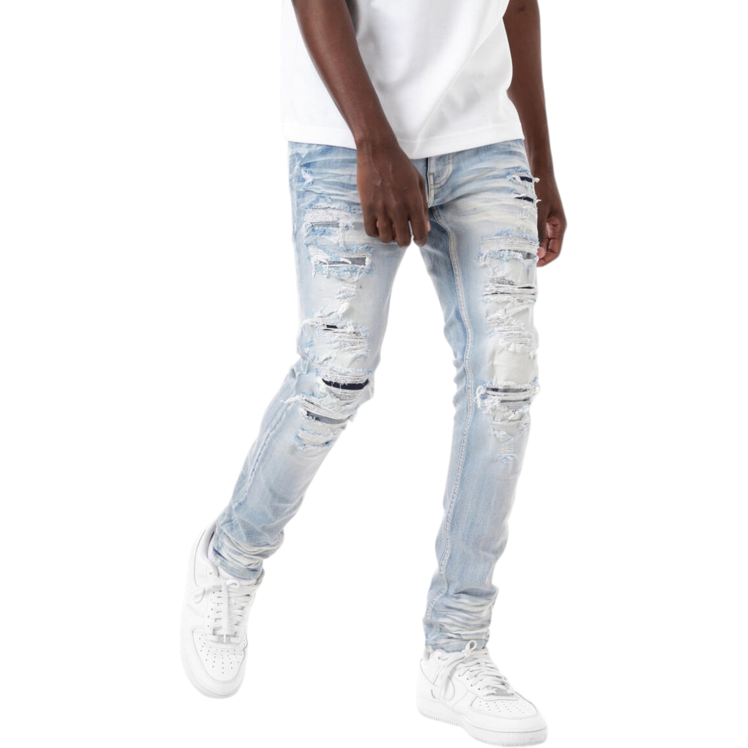 Person wearing light blue distressed jeans and white sneakers on a white background